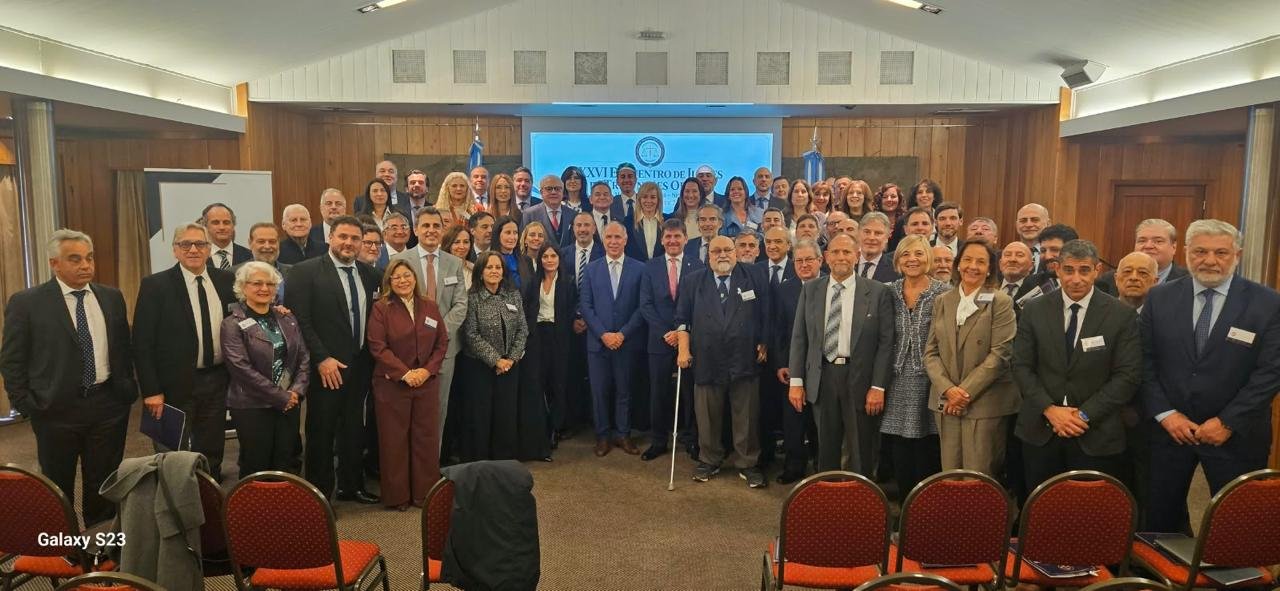 Foto oficial de los participantes del XXVI Encuentro frente a la pantalla del evento