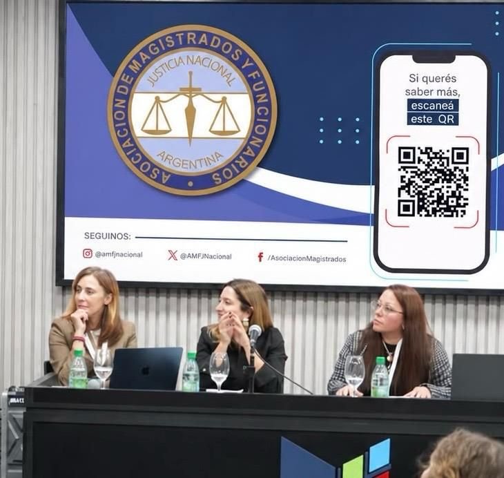 Integrantes de la Asociación en un panel frente a la pantalla institucional de la AMFJN